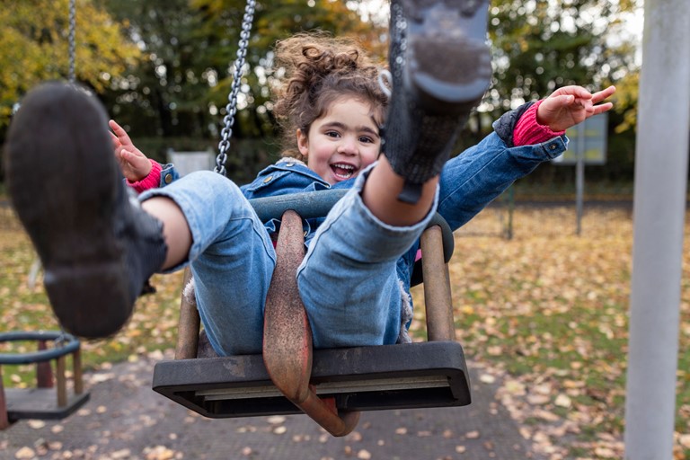 Girl playing on a swing, laughing