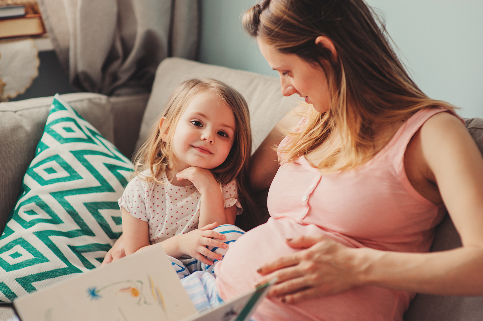 Pregnant mum and daughter on sofa