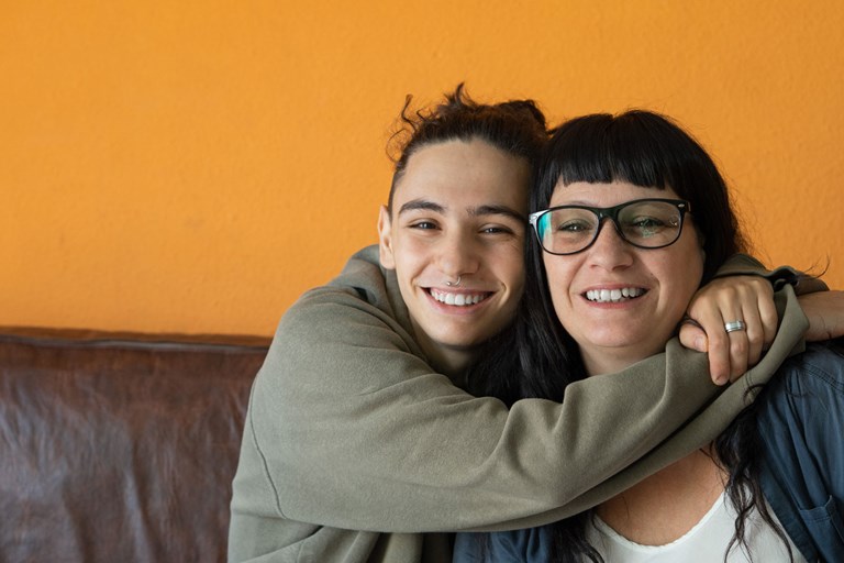 Teenager having a big hug with woman wearing glasses